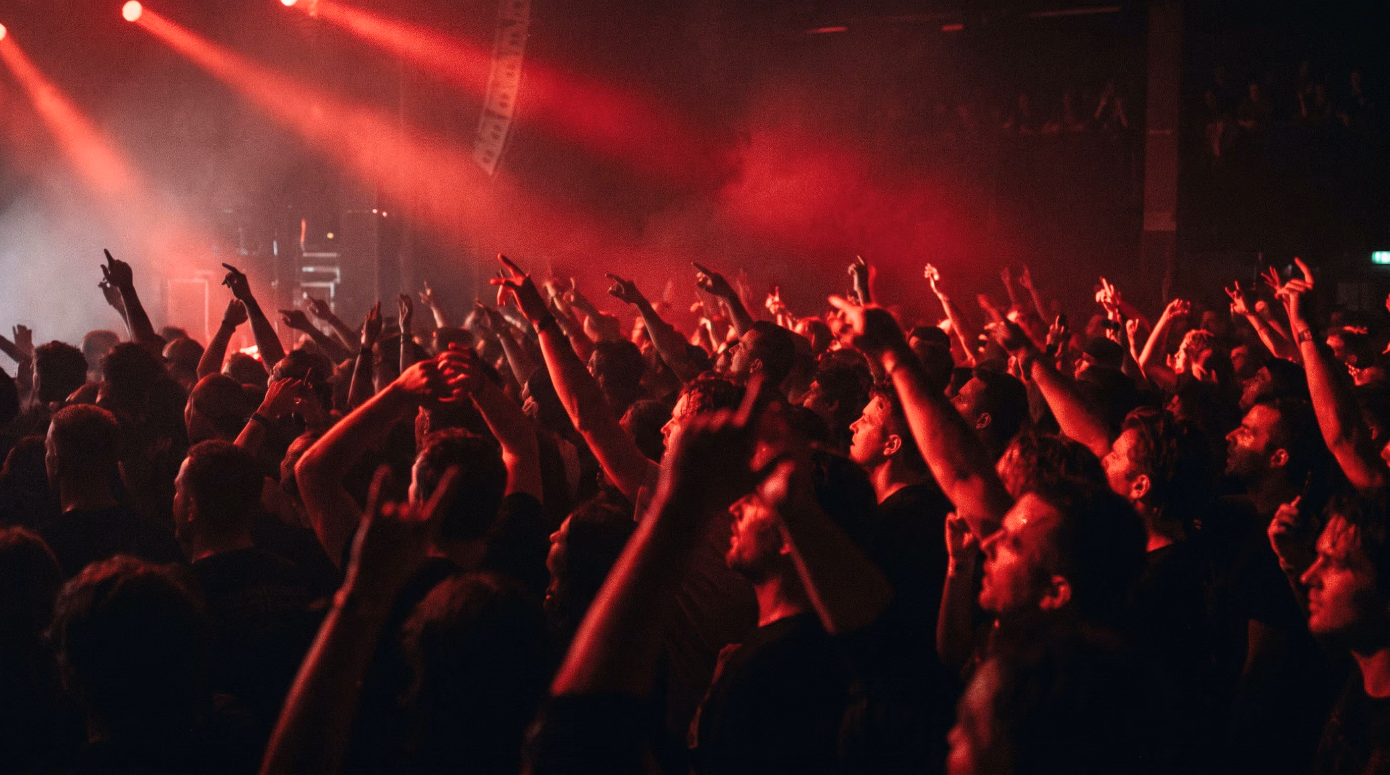 Sea of raised hands under red stage lights
