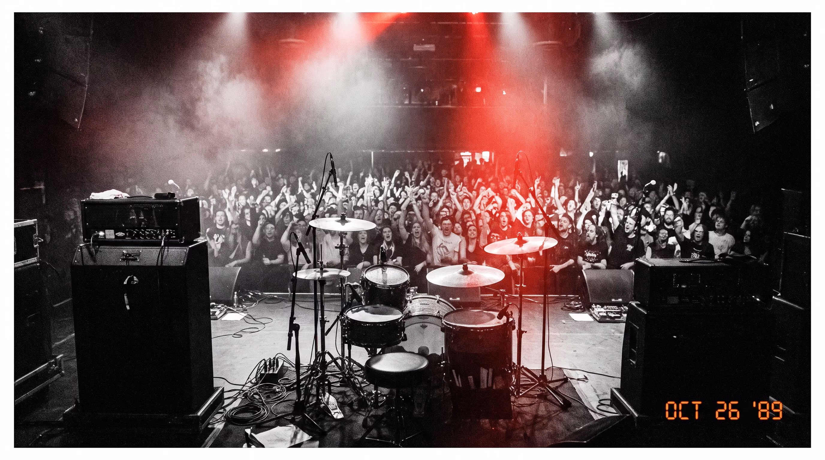 Packed concert crowd seen from the stage under red lights