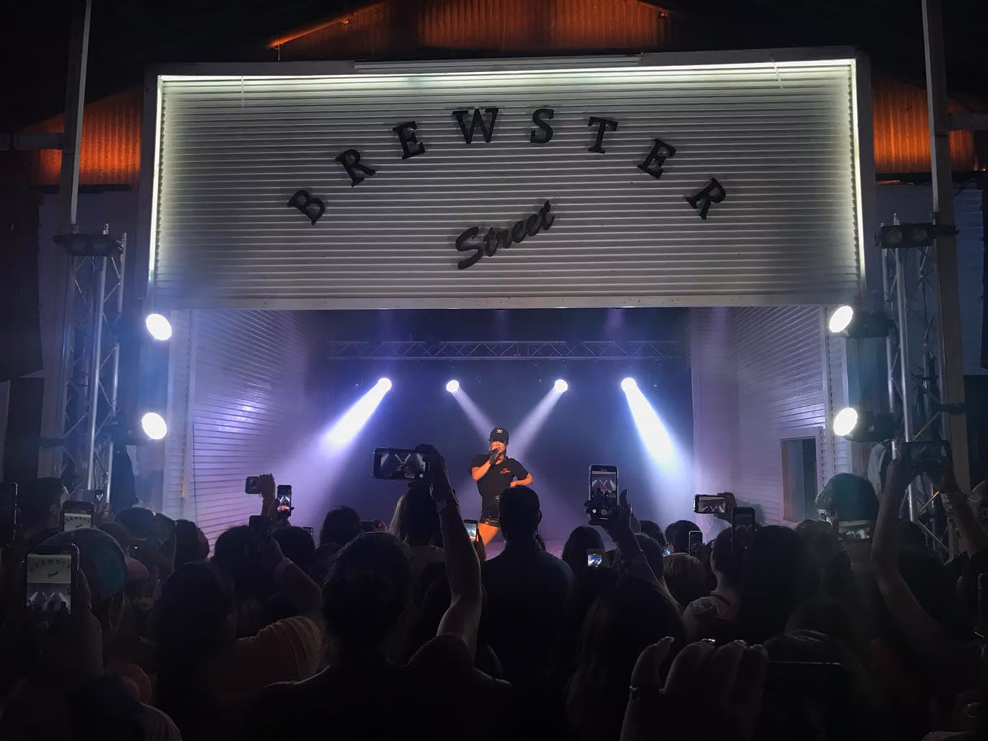 A Brewster Street crowd lit by phone screens