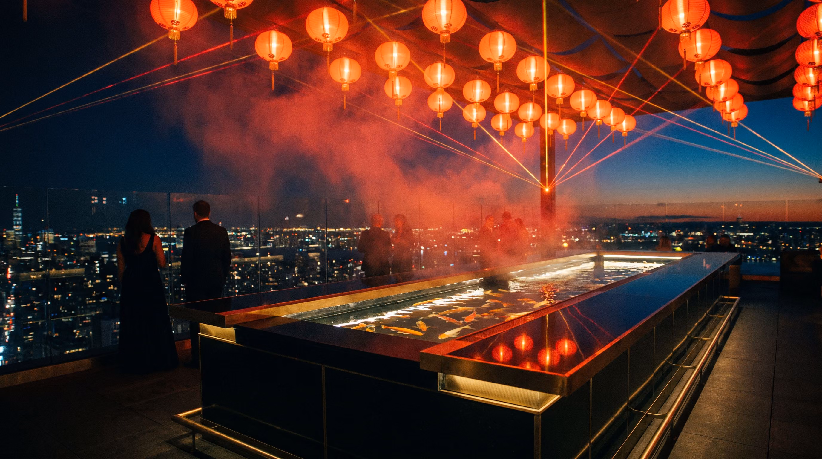 The rooftop deck at night under red lanterns, the Manhattan skyline beyond