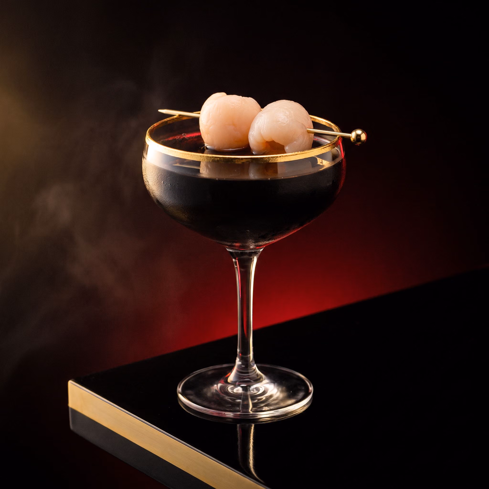 Latex and Lanterns: black vodka cocktail with a gold rim and lychees