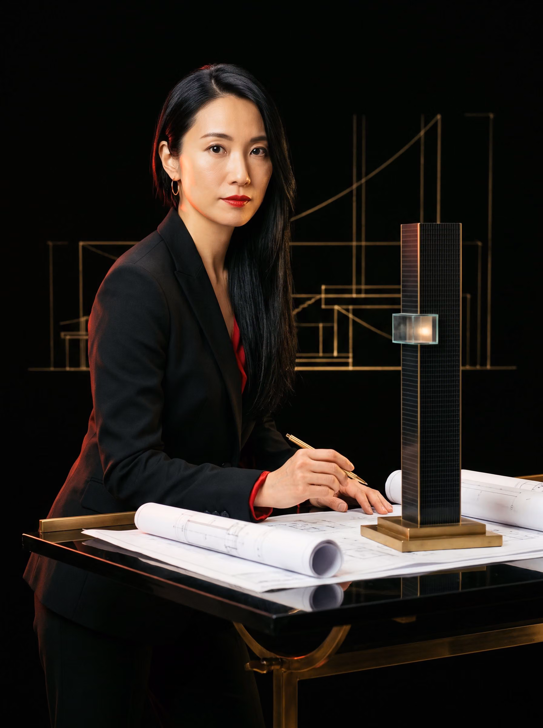 Rei Tatsumi, architect, at a lacquer drafting table with a brass model of the tower