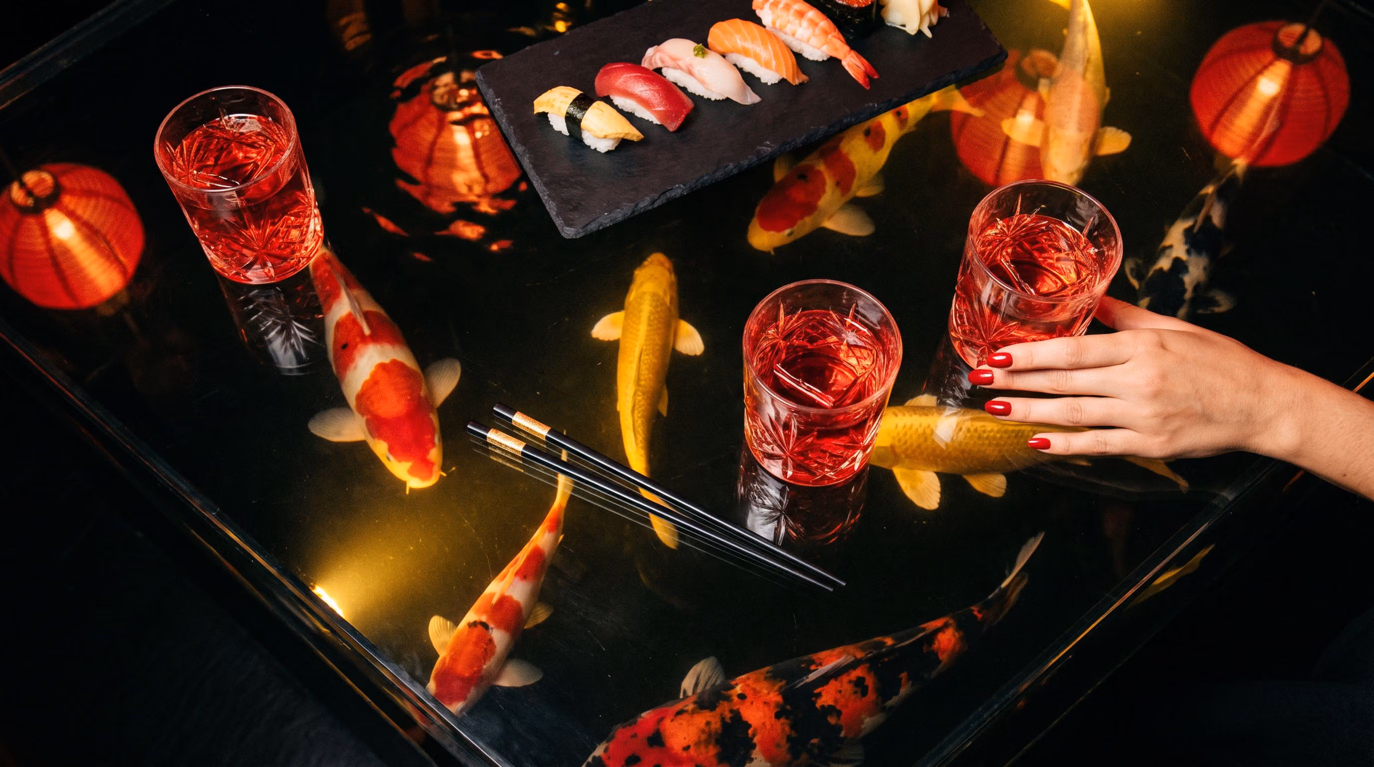 Looking down through the glass top of the Koi Bar, koi gliding beneath cocktails and nigiri
