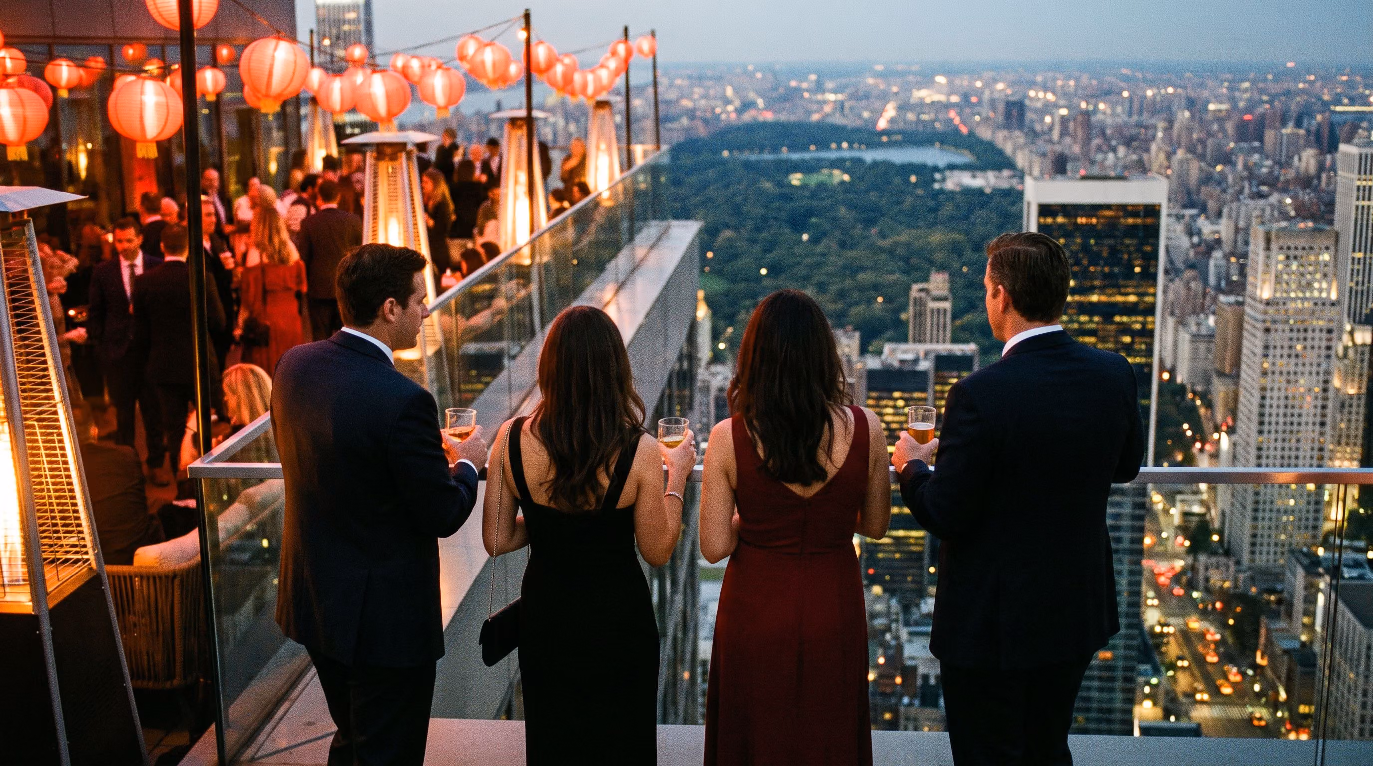 Four guests at the rooftop balustrade at 1am looking out over Central Park and Manhattan under red lanterns