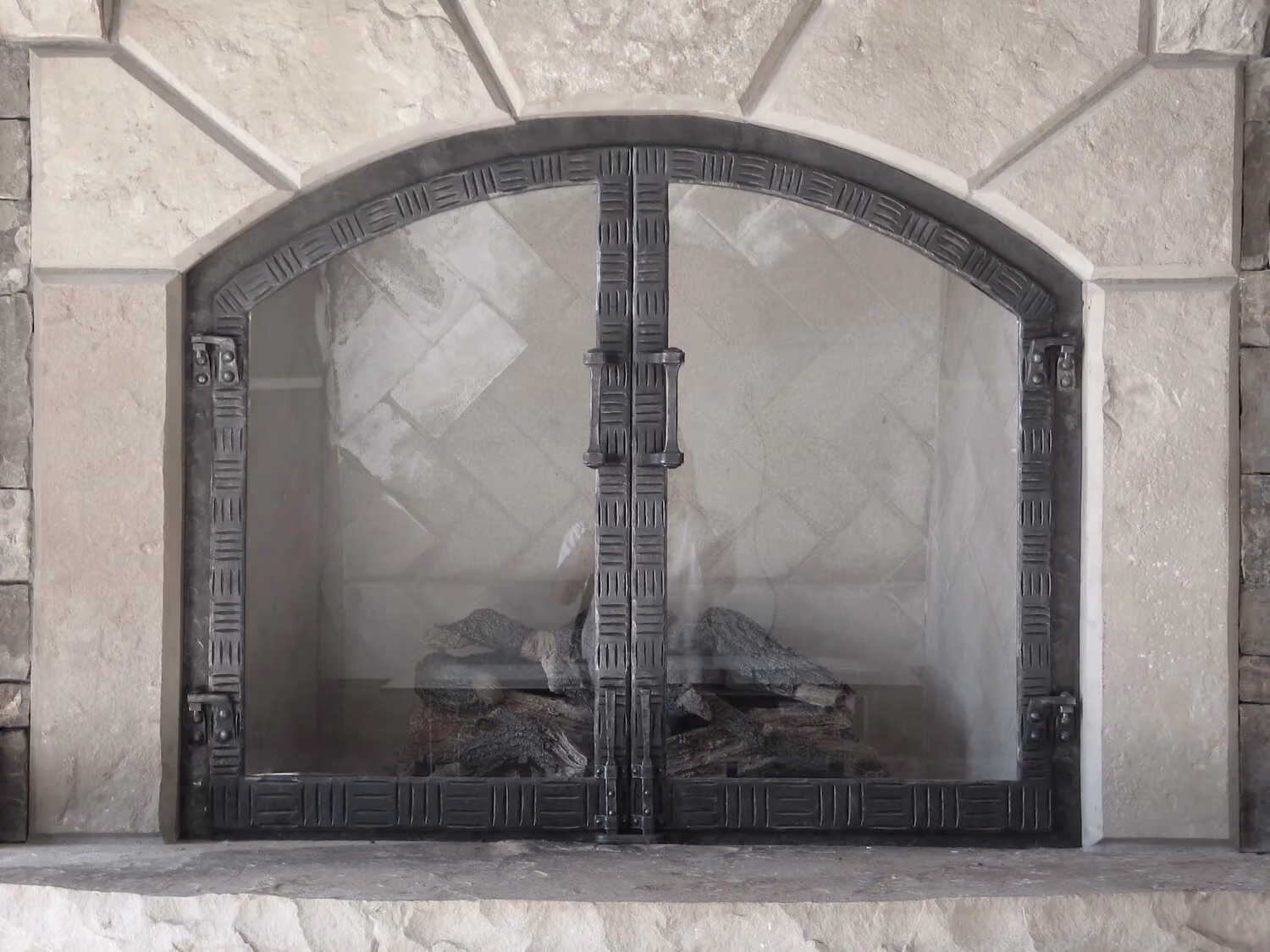 Arched fireplace doors in a stone surround