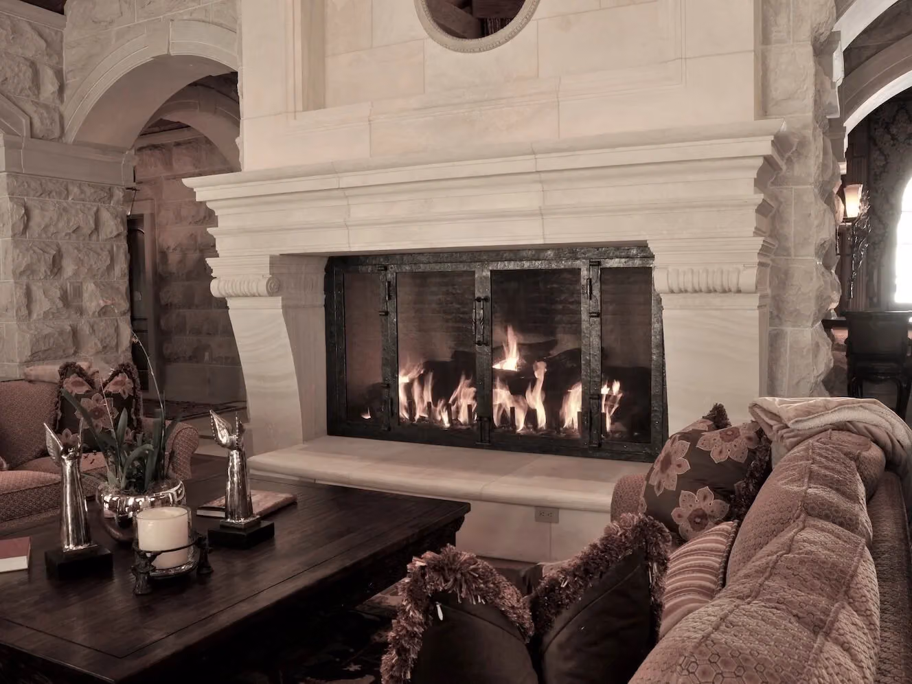 A lit fireplace behind forged doors in a stone hearth