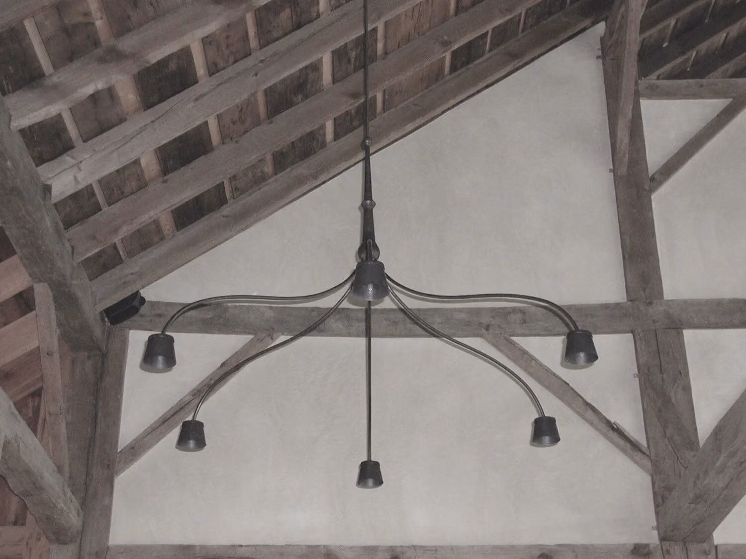 A forged light fixture hung from timber beams