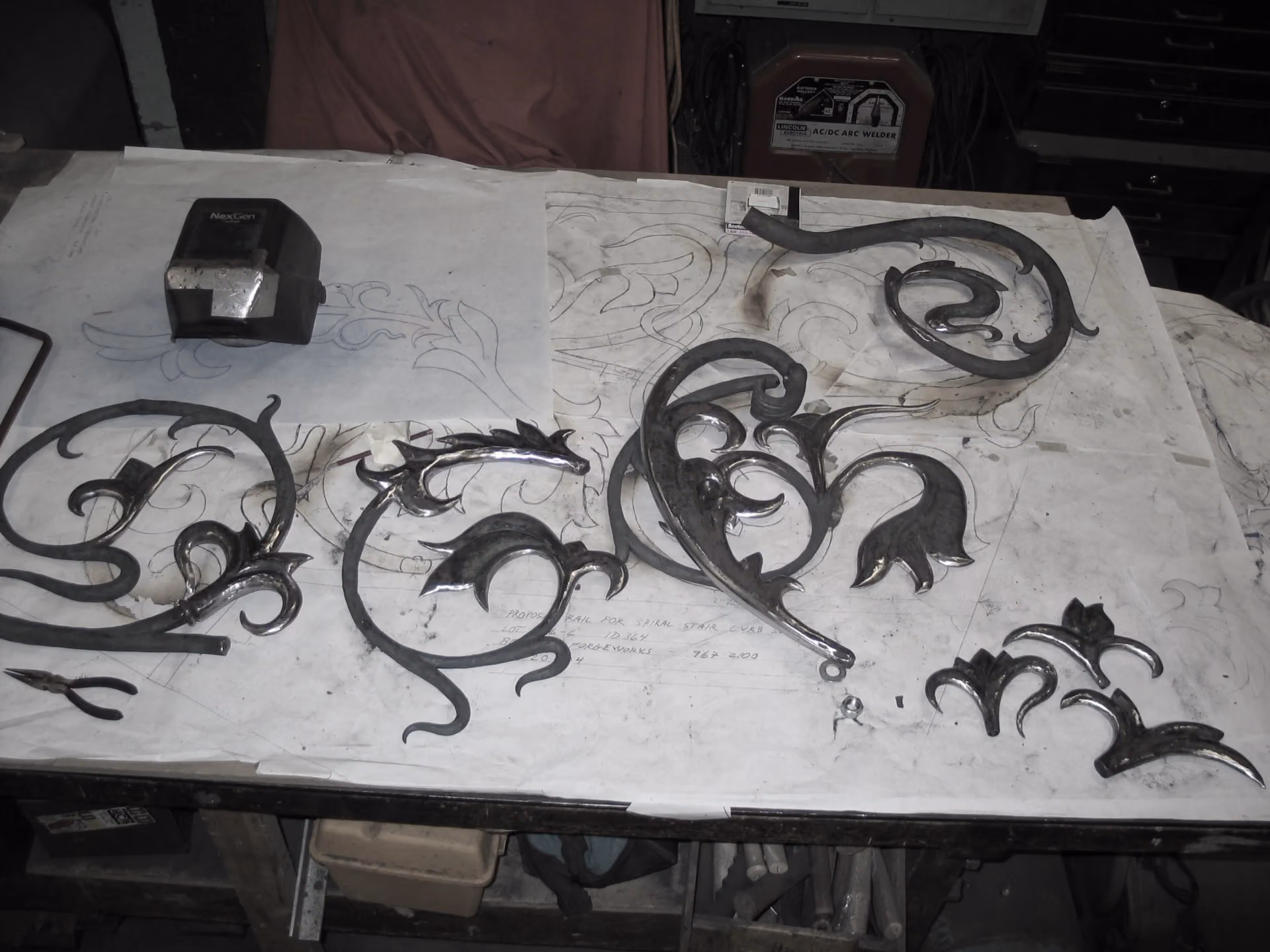 Forged leaves laid over the full-size drawing on the shop bench