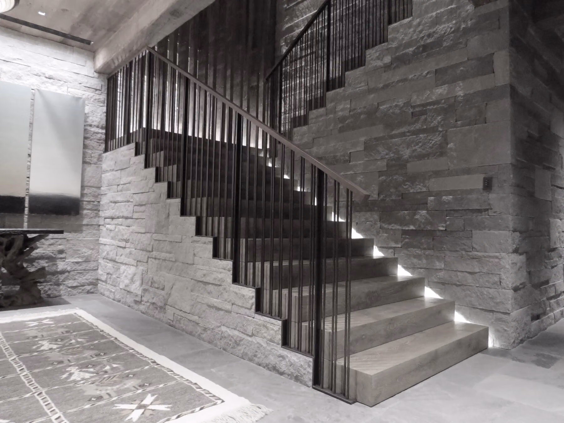 A steel stair and railing against a stone wall