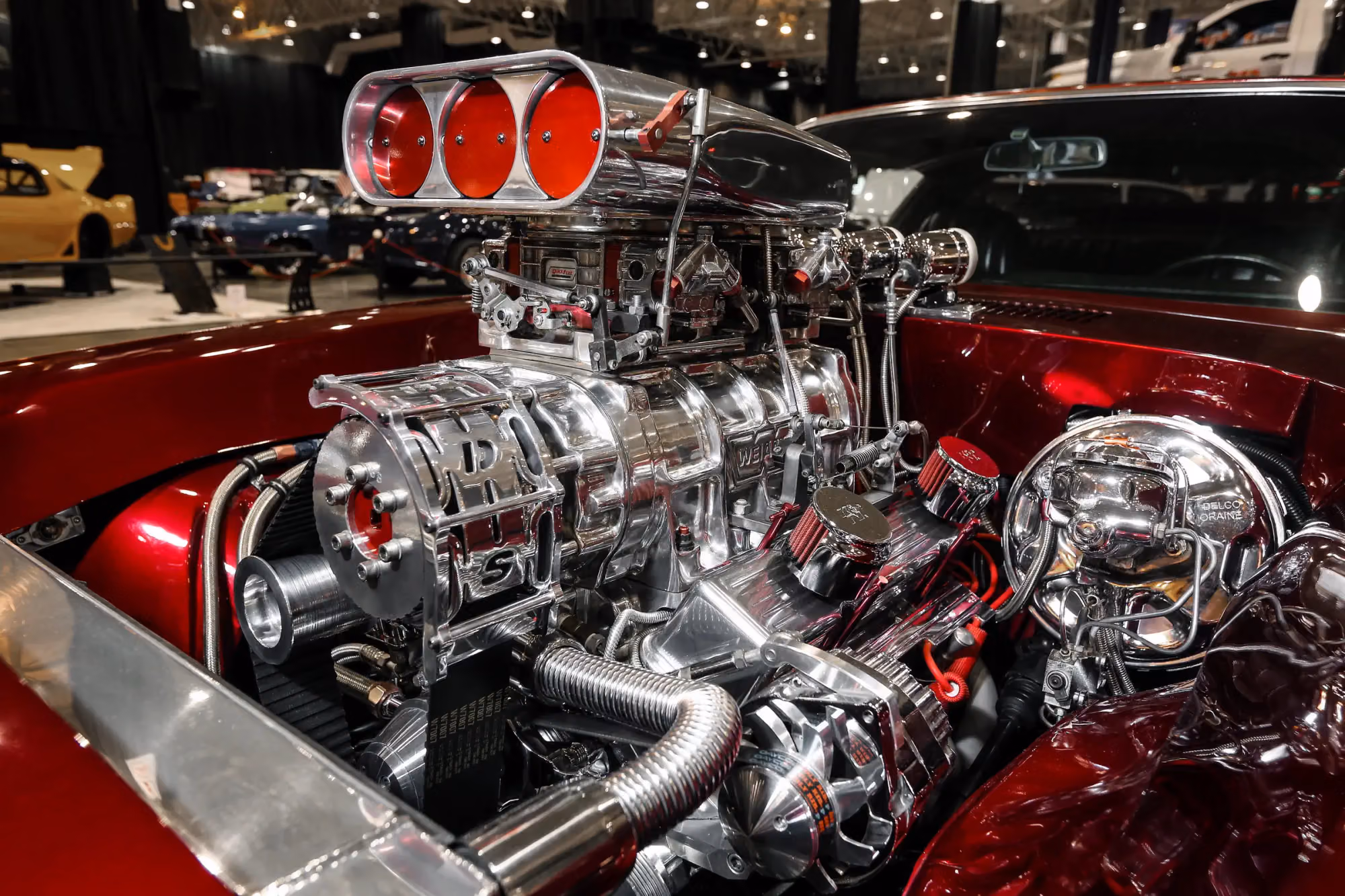 A chrome supercharger on a candy red hot rod