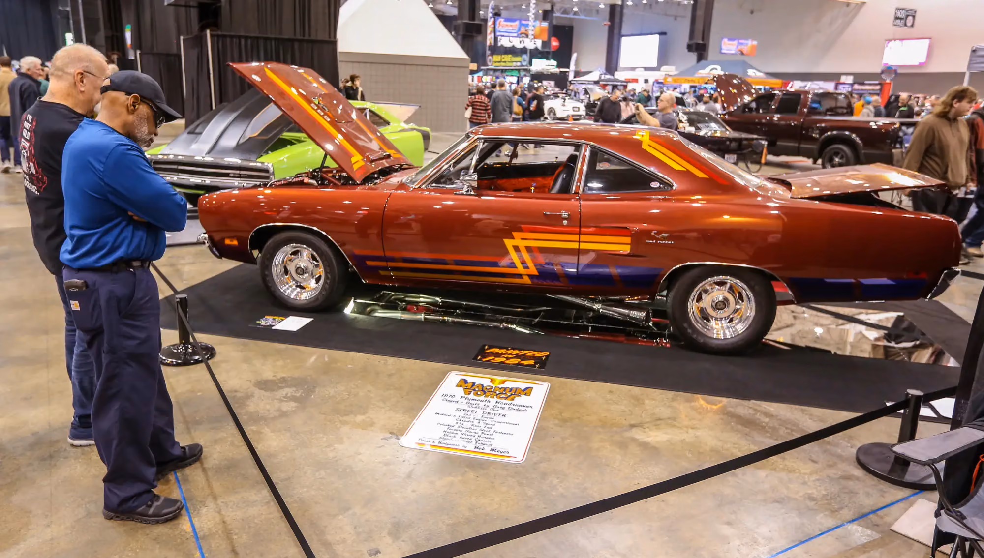 A candy red hot rod with its hood open and the crowd around it