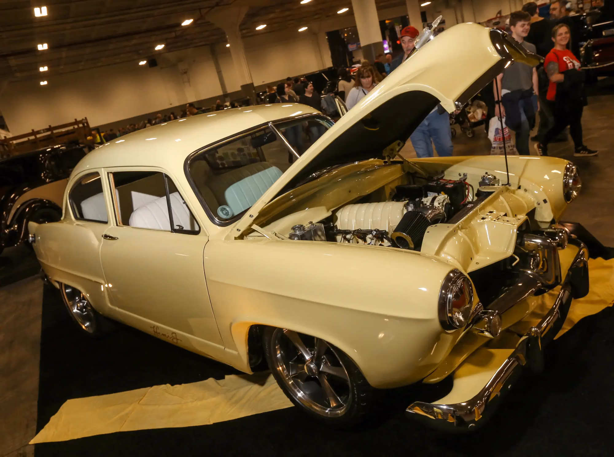 A cream fifties coupe with its hood open