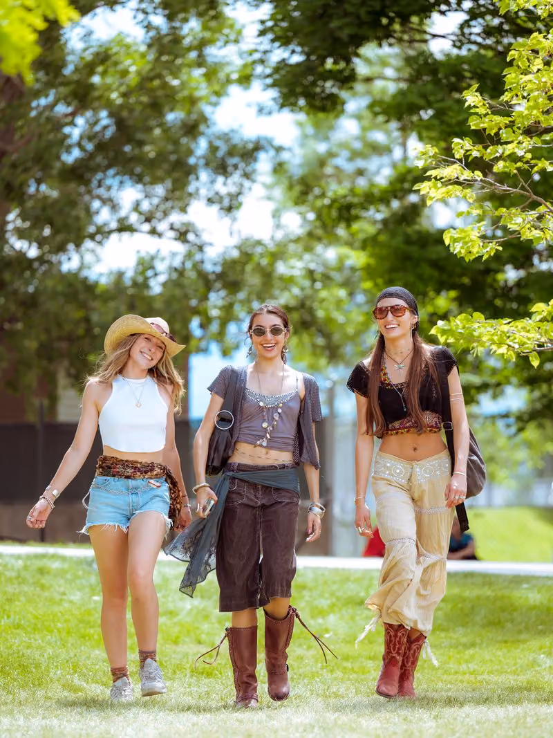 Three friends walking across the festival lawn