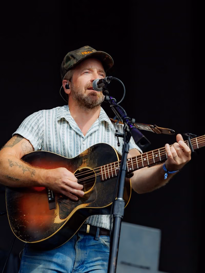 Singer in a cap playing acoustic guitar on stage