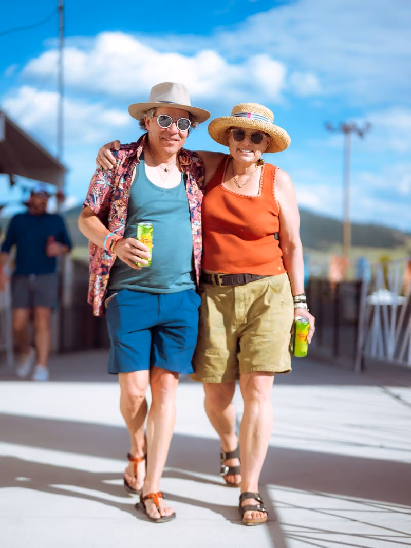 Two friends walking arm in arm through the festival grounds
