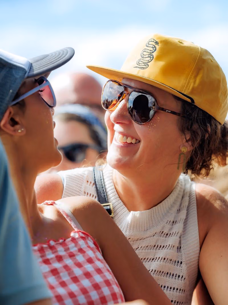 Smiling festivalgoer in sunglasses and a yellow hat