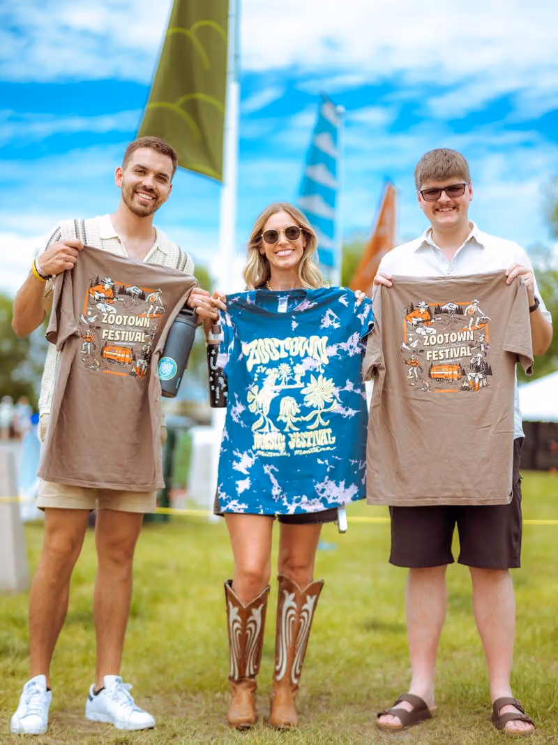 Friends holding up Zootown festival t-shirts