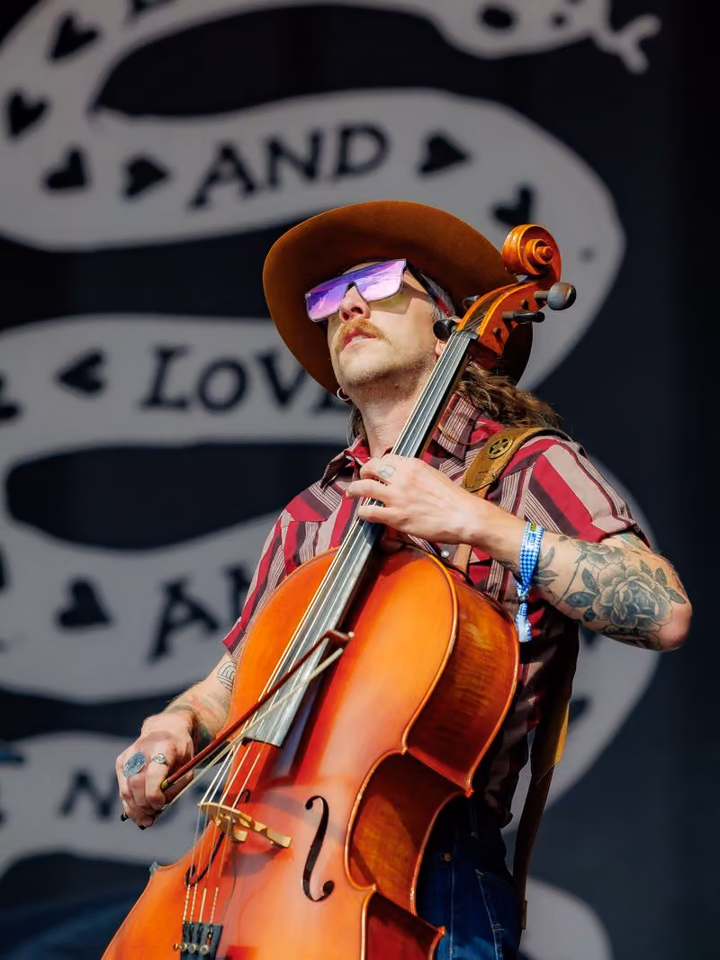 Cellist in a cowboy hat performing on stage